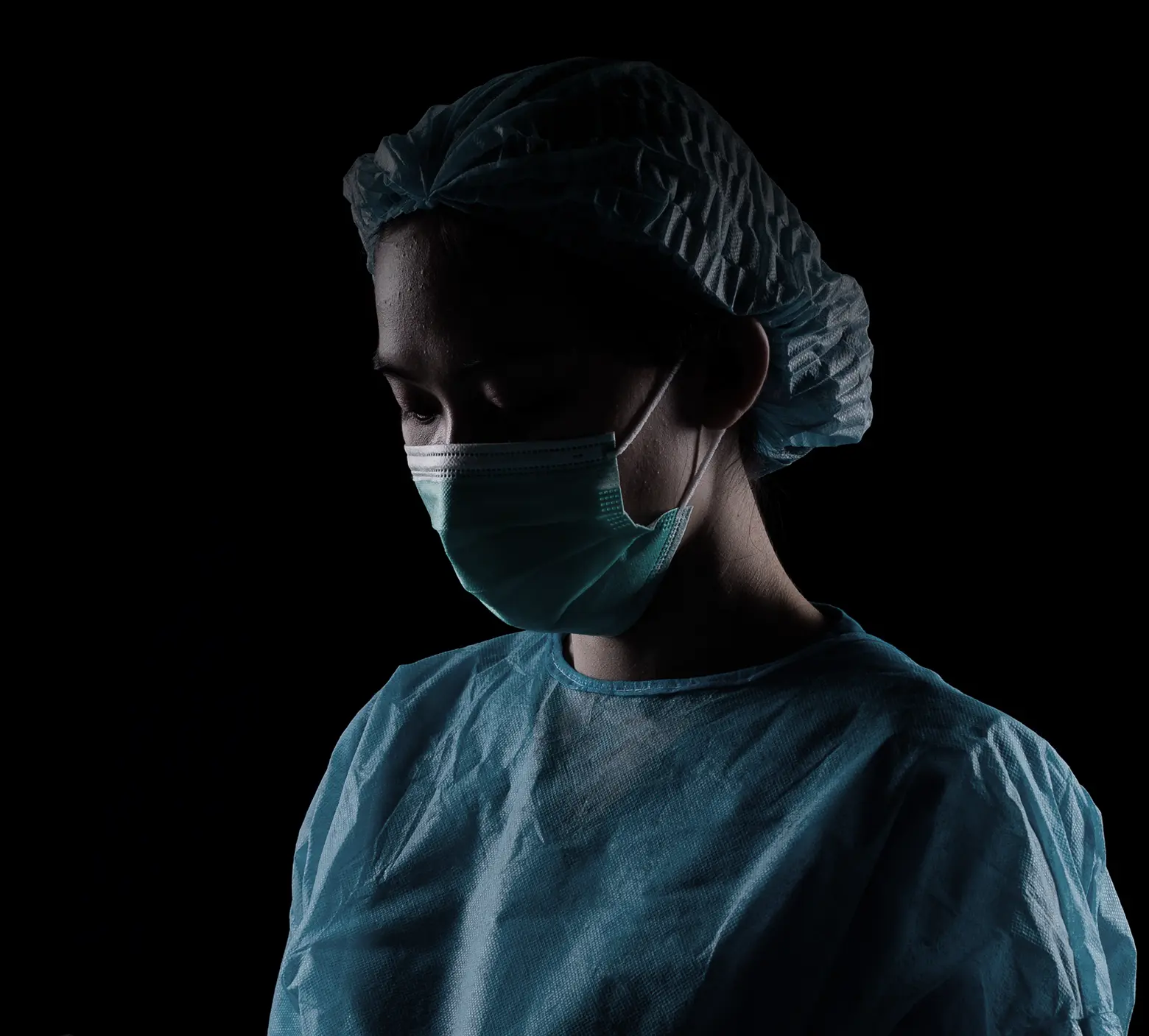Clinician in surgical cap and mask, in low light